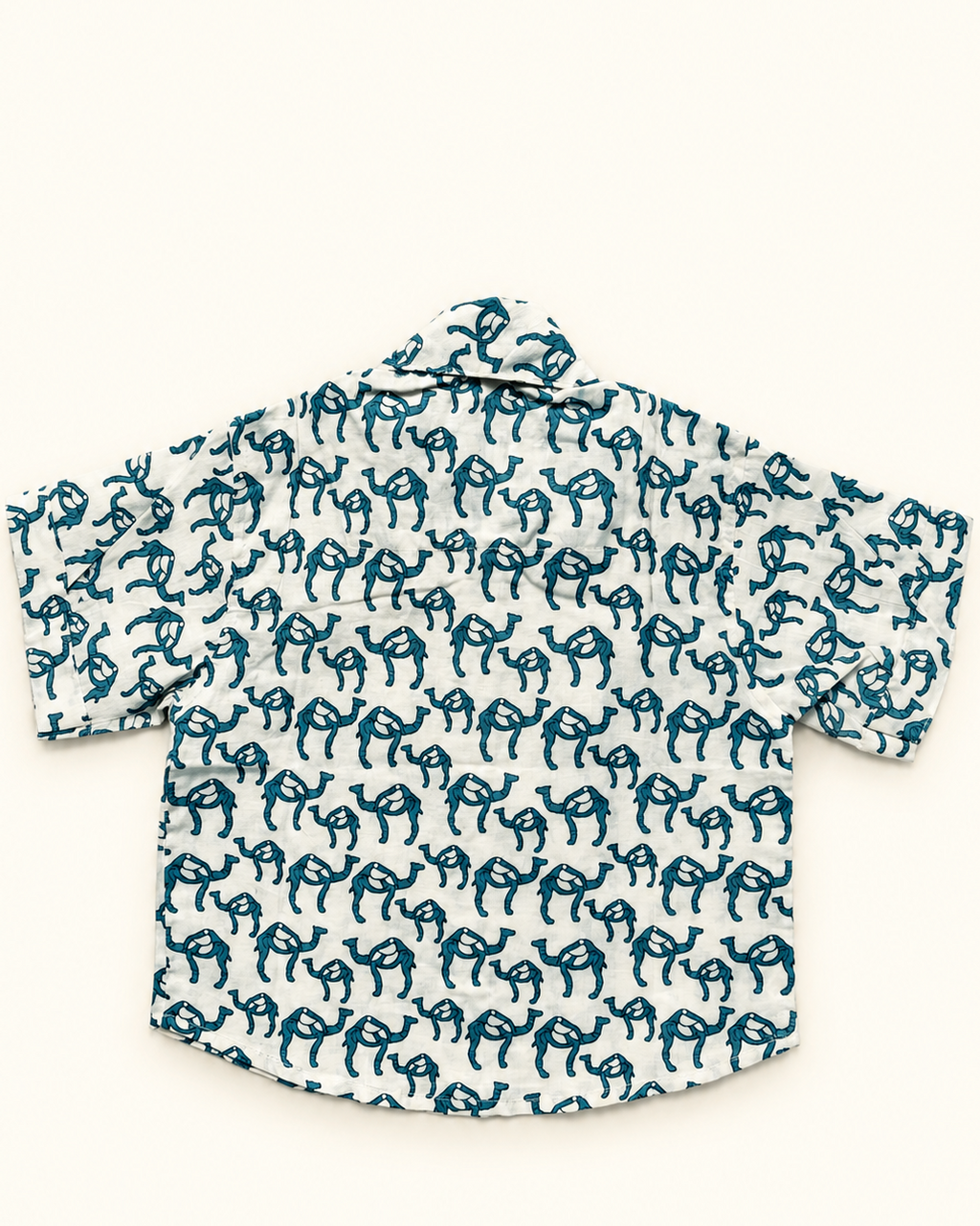 A short-sleeve button-up shirt with a white base and an all-over teal blue hand-drawn style animal print, laid flat against a light cream background.