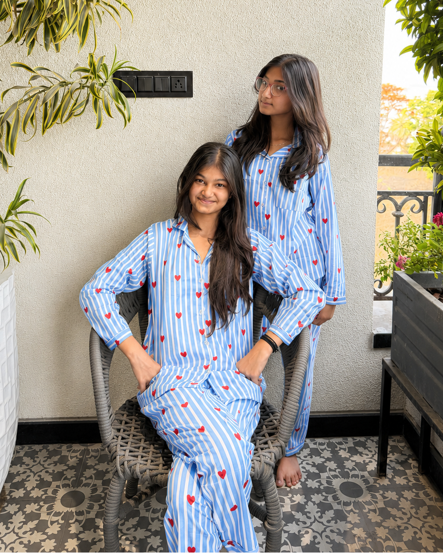 Two girls are standing wearing dreamy heart blue colored premium night suit from Aruvo, in a balcony