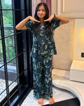 A girl is wearing a peplum styled top with matching pant in navy blue color from brand Aruvo, standing near a glass door smiling
