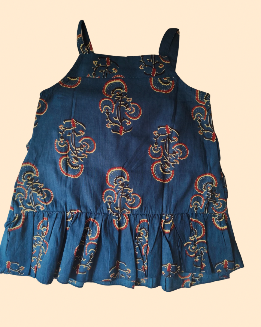 A kids strapped sleeve top shows back side , featuring a dark blue base with a red and gold paisley pattern, displayed against a solid pale beige background