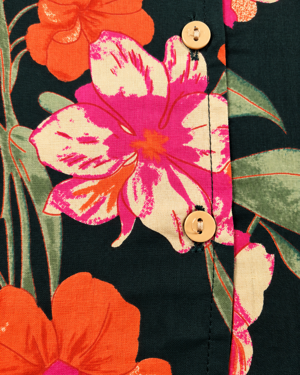 A close-up of a dark green floral shirt with orange, pink, and green hibiscus flowers, featuring a button-down front, laid flat on a light beige background.