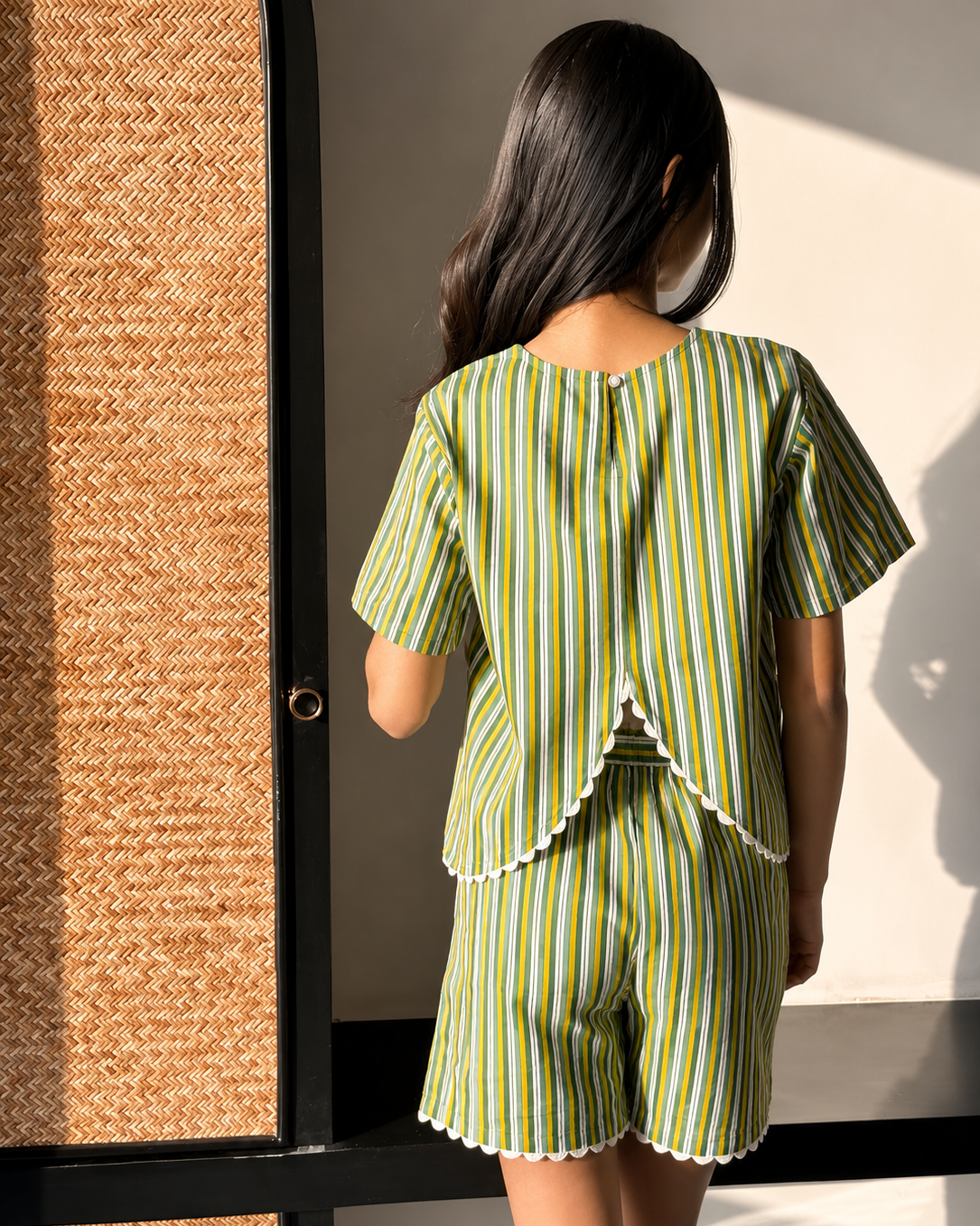 A girl wearing Aruvo's striped pure cotton stylish shorts set and standing near an open area 
