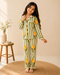 A toddler wearing premium Green striped floral printed cotton night suit set from Aruvo, standing on a rug and is smiling