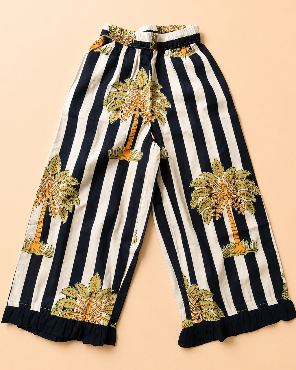 A pant of wide-leg pants featuring vertical navy stripes from Aruvo laid flat on a solid peach background.