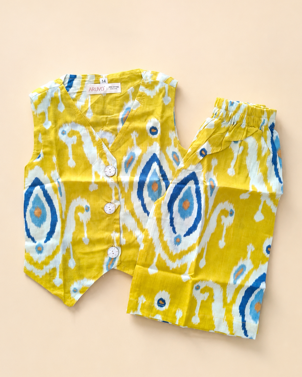 A two-piece children's outfit set consisting of a sleeveless button-front vest and matching pants, featuring a vibrant yellow base with a blue, white, and orange ikat pattern, laid flat on a light beige background.