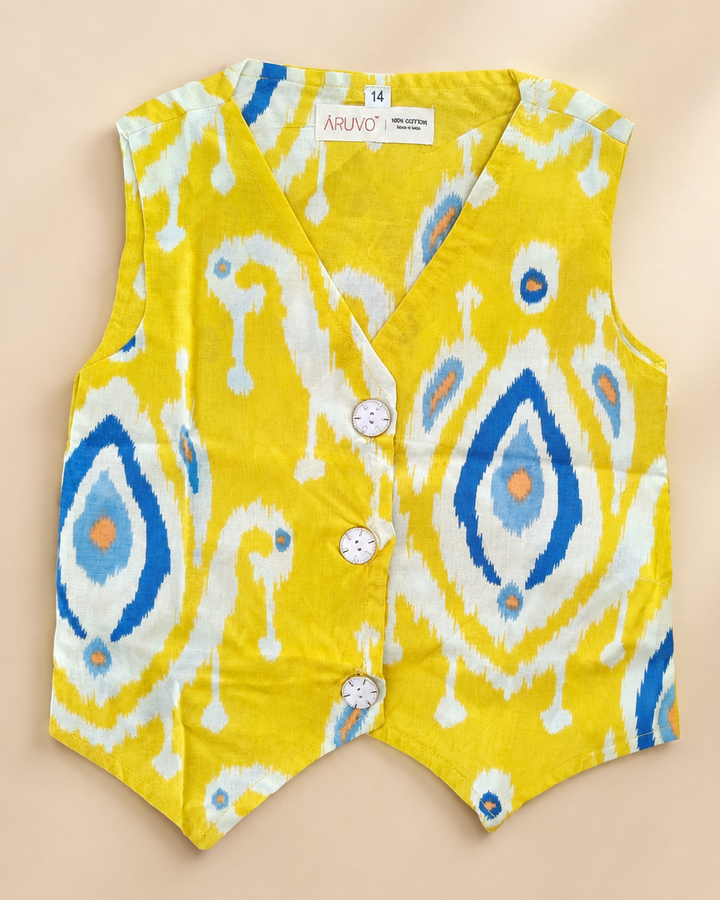 A yellow fabric garment with a blue, white, and orange ikat pattern, featuring three white buttons on the front, laid flat on a beige background.