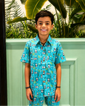 Child wearing Aruvo's blue patterned outfit, Panda prints on it standing in front of a textured wall with a plant.