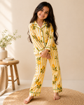 A girl is wearing premium full sleeve Yellow striped, floral printed kids night suit set from Aruvo, standing on a rug with white background
